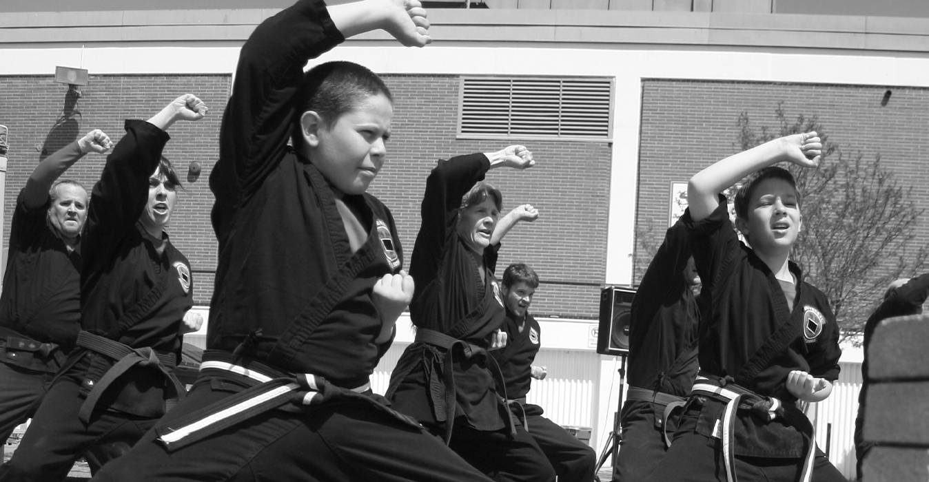 Universal Kempo-Karate students training outdoors in unison, fists raised, wearing black gis