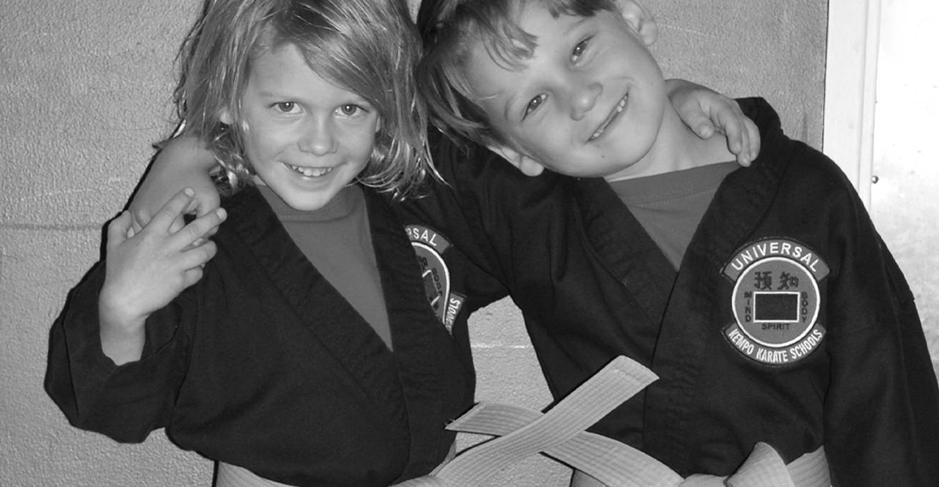 Two young karate students in black gis smiling together